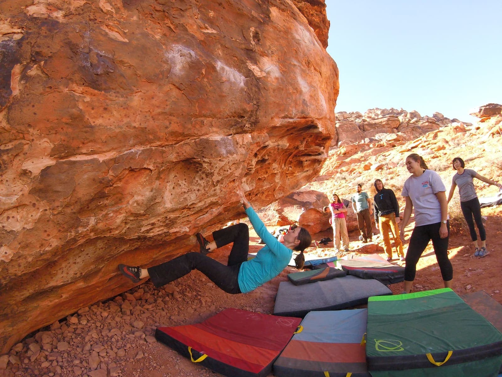 Climber managing an outdoor sandstone roof with spotters